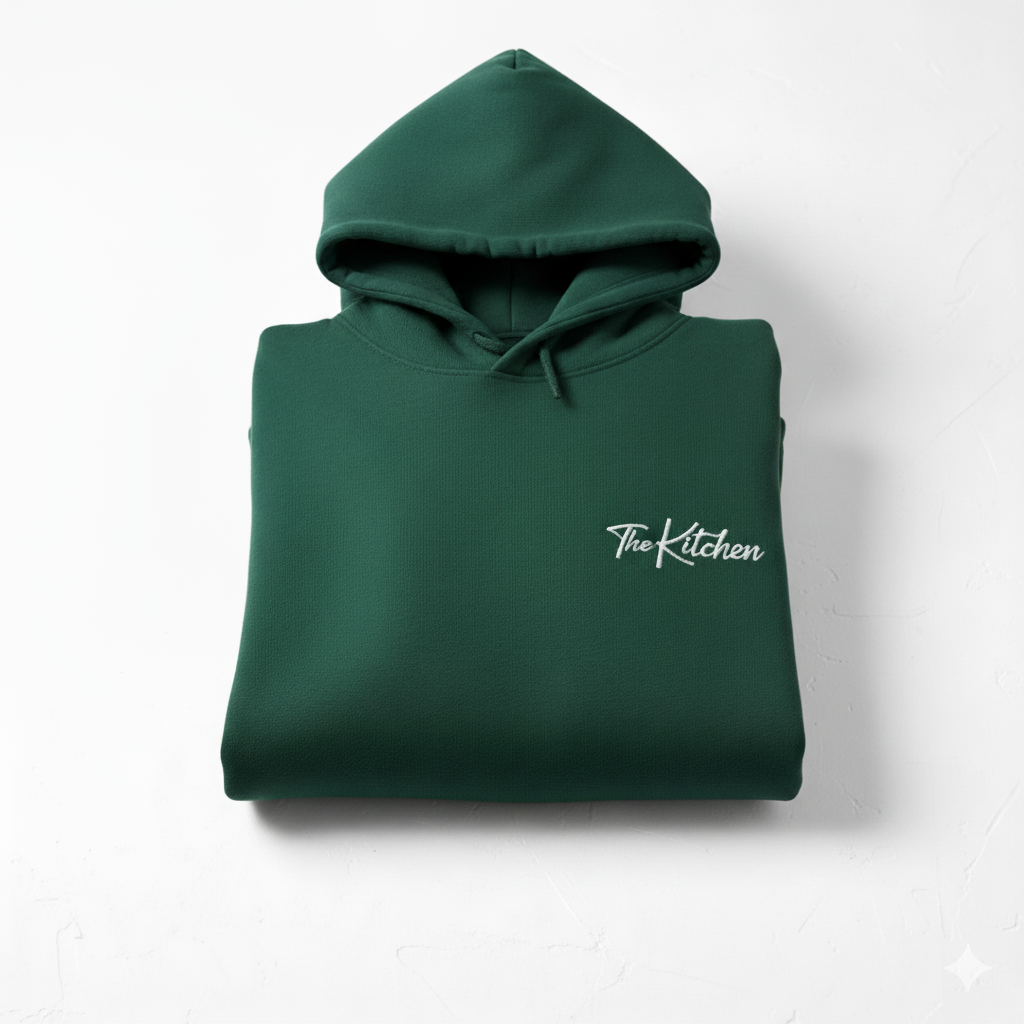 Folded green hoodie with 'The Kitchen' logo on a white background