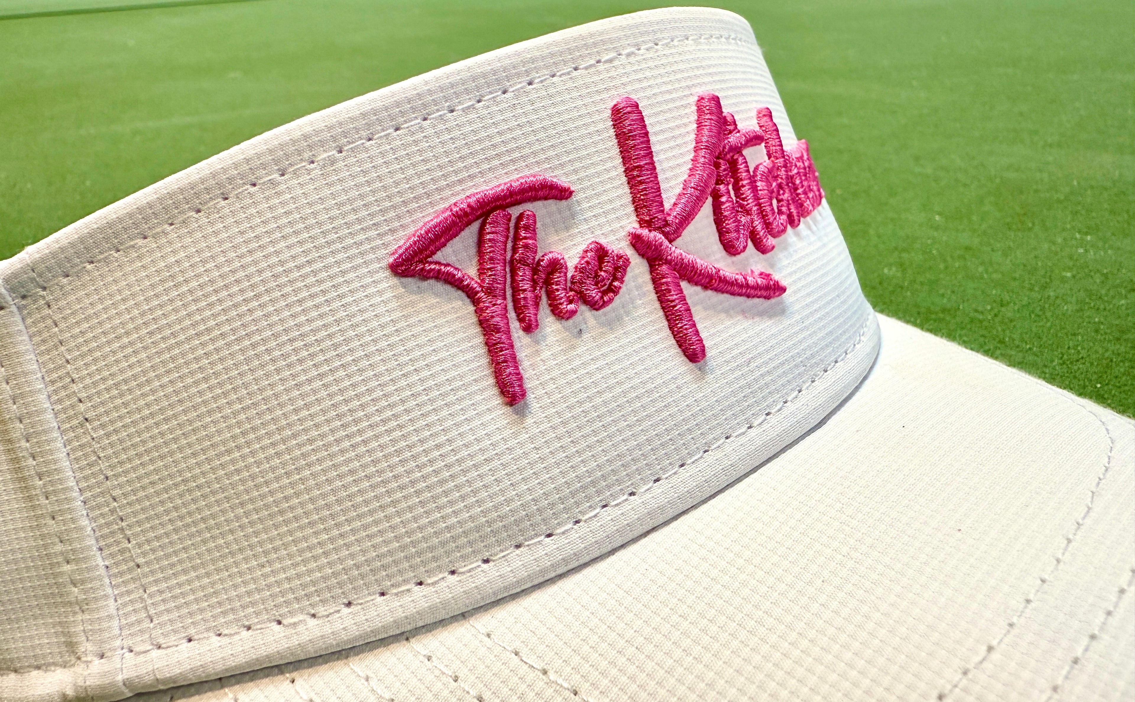 white visor with pink logo close up shot on turf background